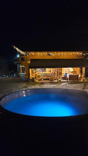 ein blauer Pool vor einem Gebäude in der Nacht in der Unterkunft ORTOAIA CHALET in Dorna-Arini
