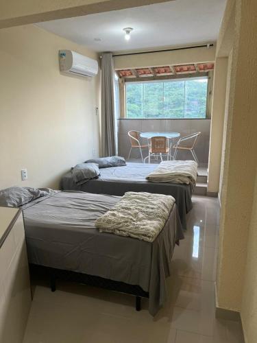 two beds in a room with a table and a table at Pousada Recanto do Canário 2 in Governador Celso Ramos