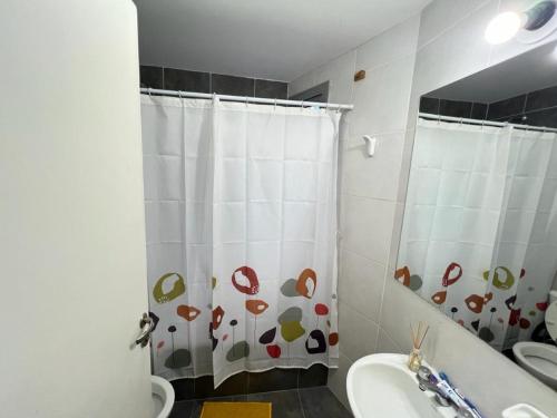 y baño con cortina de ducha y lavamanos. en Dpto Duplex a metros de la Terminal en Salta