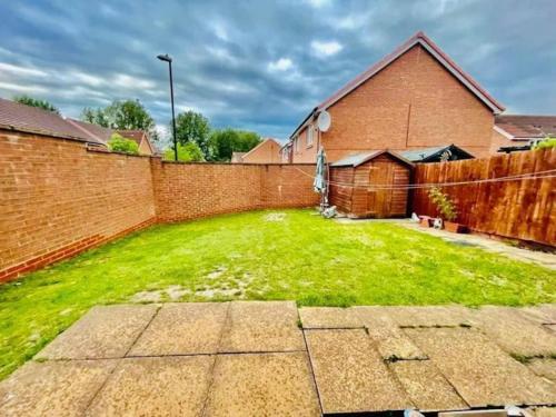 a yard with a brick wall and a fence at 3 Bedroom Affordable Family Detached House - Business Contractors, Midlands Location - Private garden,Free car park,TV- Netflix and Free WiFi in Coventry