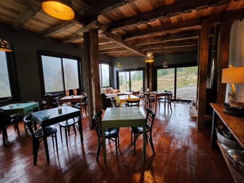 a dining room with tables and chairs and windows at k10lodge in Curacautín
