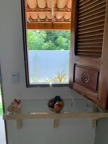 una finestra in una cucina con una ciotola di frutta su uno scaffale di II Chalés O Sertanejo BG a Barra Grande
