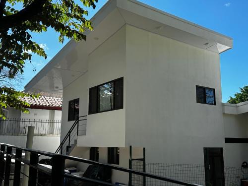 a white house with black windows and a balcony at Peaceful Apartment in Tamarindo, 50m to the Beach - Sofia Apartments in Tamarindo