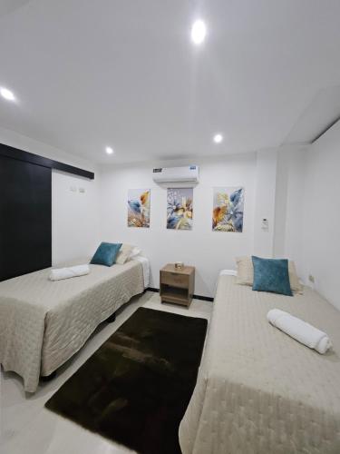 2 camas en una habitación blanca con pinturas en la pared en Urbanizacion privada "El Sol", Villa K2 en Machala