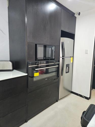 a kitchen with a refrigerator and a microwave at Urbanizacion privada "El Sol", Villa K2 in Machala