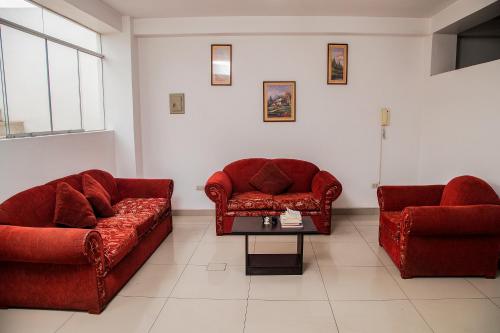 ein Wohnzimmer mit zwei roten Sofas und einem Tisch in der Unterkunft Lujoso Departamento ,Iluminado , 5 minutos Centro in Tacna