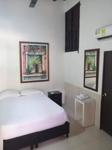 um quarto com uma cama branca num quarto em Hotel Casablanca de Santodomingo em Aguachica