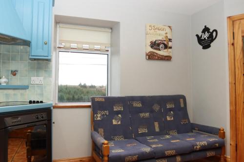 a living room with a blue couch and a window at Biddy Rua's Place in Killybegs