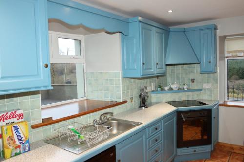 a kitchen with blue cabinets and a sink at Biddy Rua's Place in Killybegs