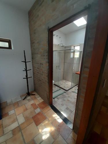 a bathroom with a shower and a glass door at Casona de Barro in Imbassai
