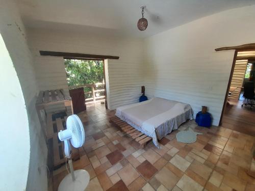 1 dormitorio con 1 cama y suelo de madera en Casona de Barro, en Imbassai