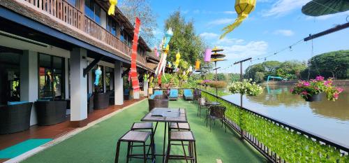 a row of tables and chairs on a balcony next to a river at Club One Seven Gaymen Chiang Mai in Chiang Mai