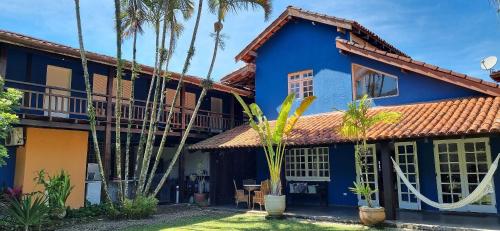 a blue house with palm trees in front of it at Maresias de Itu Suites pertissimo da praia com piscina in Maresias