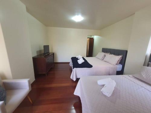 una camera d'albergo con due letti con lenzuola bianche di Aconchegante no centro de Nova Friburgo a Nova Friburgo