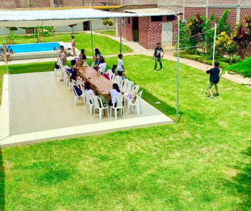 um grupo de pessoas sentadas em torno de uma mesa na grama em Villa Mia - Casa de campo em Moche