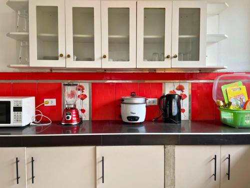 una cocina con armarios blancos y una pared roja en Villa Mia - Casa de campo, en Moche