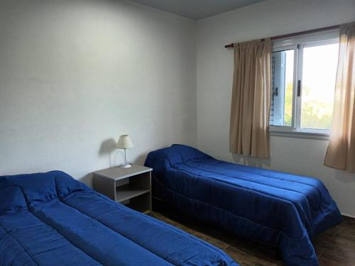 1 dormitorio con 2 camas azules y ventana en Complejo - LA ZULA - en Federación