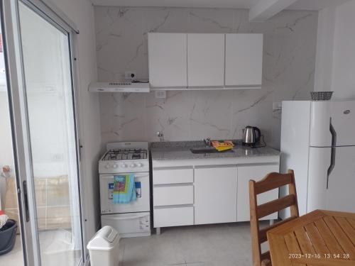 a white kitchen with a stove and a refrigerator at Rico in Mar de Ajó