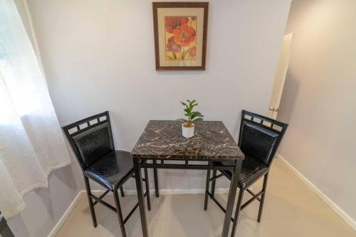 a table with two chairs and a potted plant on it at Hibiscus Cottage (Mercy's Place) in Buckleys