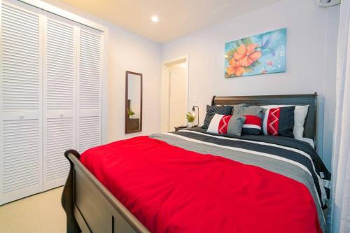 a bedroom with a large bed with a red blanket at Hibiscus Cottage (Mercy's Place) in Buckleys