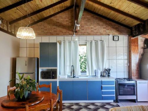 - une cuisine avec des armoires bleues et une table dans une pièce dans l'établissement Casa Pôr do Sol com churrasqueira ar condicionado, à Florianópolis