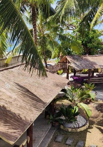a resort with a straw roof and some palm trees at Lagnason's Place in Oslob