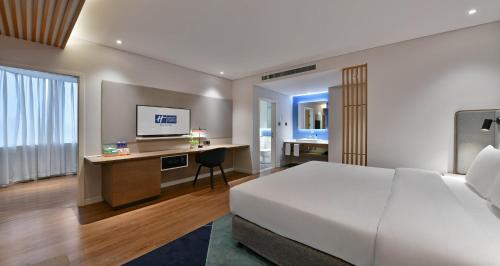 a bedroom with a bed and a desk with a television at Holiday Inn Express Chengdu North Railway Station by IHG - Near Panda Base, Near Chunxi Road in Chengdu