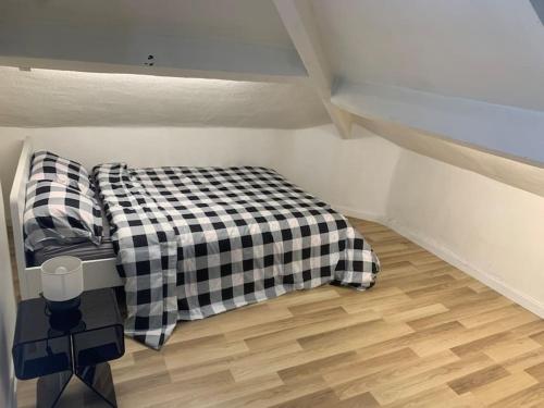 Cette petite chambre comprend un lit avec une couverture en damier. dans l'établissement Coquet Appartement 2 pièces, à Alfortville