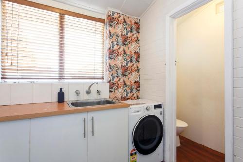 a kitchen with a washing machine and a sink at Cosy Cottage Coolbellup in Spearwood
