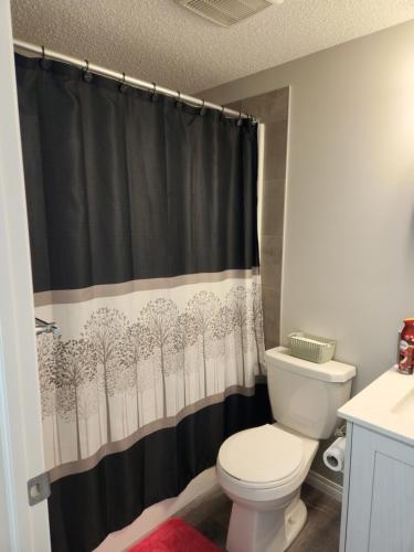 y baño con aseo y cortina de ducha negra. en Cozy entire suite!, en Calgary