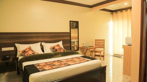 1 dormitorio con 1 cama grande y 1 mesa en Triple Tee Gardens & Accomodation, en Wakiso