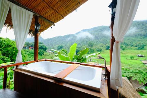a bath tub with a view of a mountain at Imsuk Bo Klua in Ban Pha Khap
