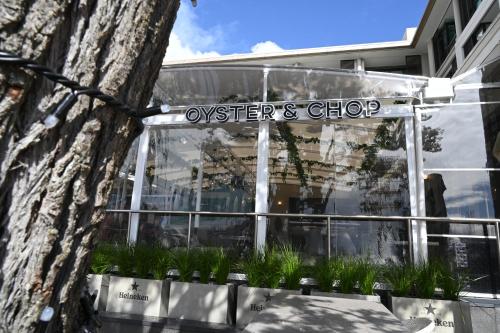 a sign for a oysters shop in front of a tree at Luxurious & Spacious Living with Breathtaking Views in Auckland