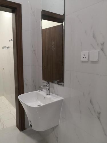 شقق جادة قباء في المدينة المنورة: حمام أبيض مع حوض ومرآة