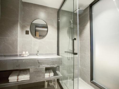 a bathroom with a sink and a glass shower at Thank Inn Chain Hotel Hunan Huaihua Hecheng District South High Speed Rail Station in Huaihua