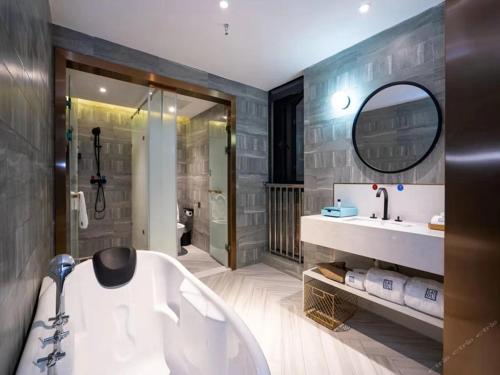 bagno con vasca, lavandino e specchio di Lano Hotel Guiyang High Speed Rail North Station Dream City a Guiyang