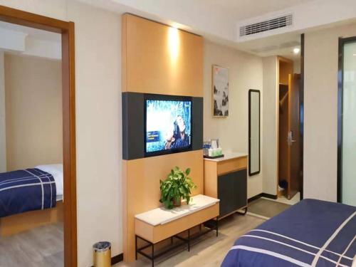 ein Hotelzimmer mit einem TV und einem Bett in der Unterkunft LanOu Hotel Bengbu Huaishang Wanda Plaza Yiwu Trade City in Bengbu