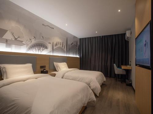 a hotel room with two beds and a flat screen tv at Thank Inn Chain Hotel Hunan Huaihua Hecheng District South High Speed Rail Station in Huaihua