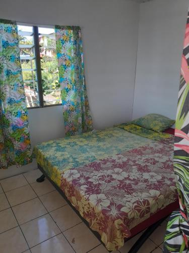 a small bed in a room with windows at Ravehei smile papeete punaauia in Papeete
