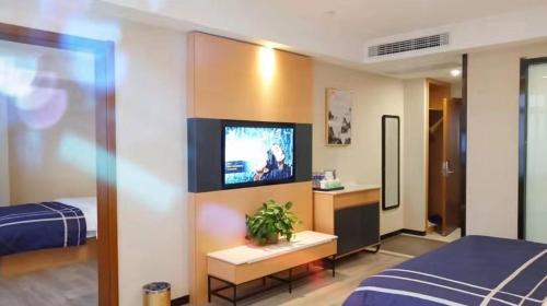 ein Hotelzimmer mit einem Bett und einem Flachbild-TV in der Unterkunft LanOu Hotel Bengbu Huaishang Wanda Plaza Yiwu Trade City in Bengbu