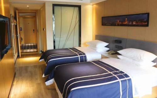 two beds in a hotel room with a large window at LanOu Hotel Zhanjiang Lvmin Road Wanhao in Zhanjiang