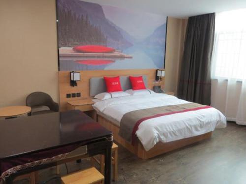 Un dormitorio con una cama con almohadas rojas y un piano en Thank Inn Chain Hotel Shangrao Houjiagang Poyang, 