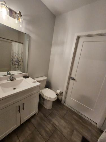 a bathroom with a toilet and a sink and a mirror at Stylish Modern 2BR Mins to NYC! in Jersey City