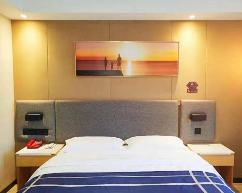 ein Schlafzimmer mit einem Bett mit zwei Nachttischen und einem Gemälde in der Unterkunft LanOu Hotel Bengbu Huaishang Wanda Plaza Yiwu Trade City in Bengbu
