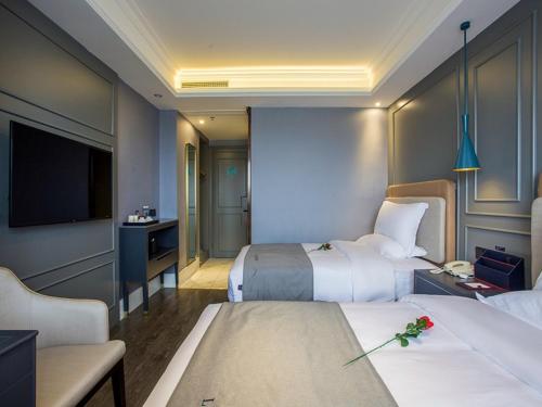 a hotel room with two beds and a television at Lano Hotel Zhenjiang South High-speed Railway Station Baolong Plaza in Zhenjiang