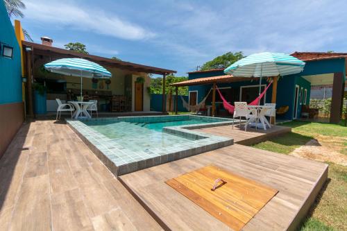 una casa con piscina e due ombrelloni di Casa Praia Gaúcho Santo Antônio DIOGO a Mata de Sao Joao