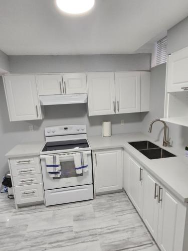 a white kitchen with white cabinets and a stove at SUITE A 2 Bedroom Apartment in Brampton