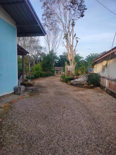 a dirt road next to a house and a tree at Baan Namthip Homestay Trang บ้านน้าทิพย์ โฮมสเตย์ตรัง in Ban Huai To (1)