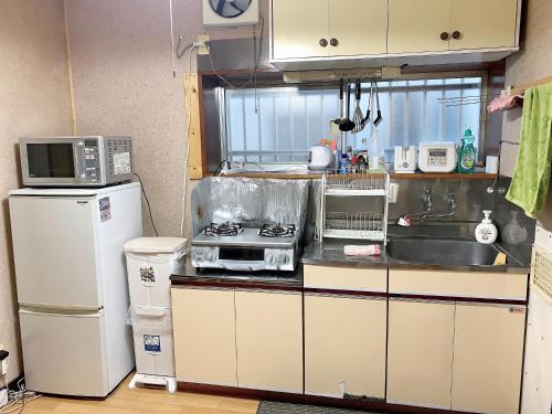 La cuisine est équipée d'un évier, d'une cuisinière et d'un four micro-ondes. dans l'établissement Tokyo Kamakura House, à Tokyo