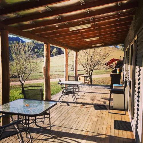 a patio with tables and chairs on a wooden deck at Artshack@Wilgabah in Wallabadah